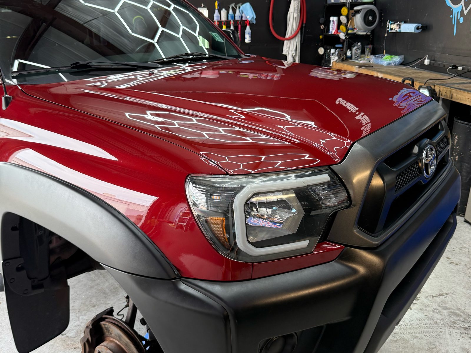 Red Toyota Tacoma hood with mirror gloss reflecting the hex shop lights
