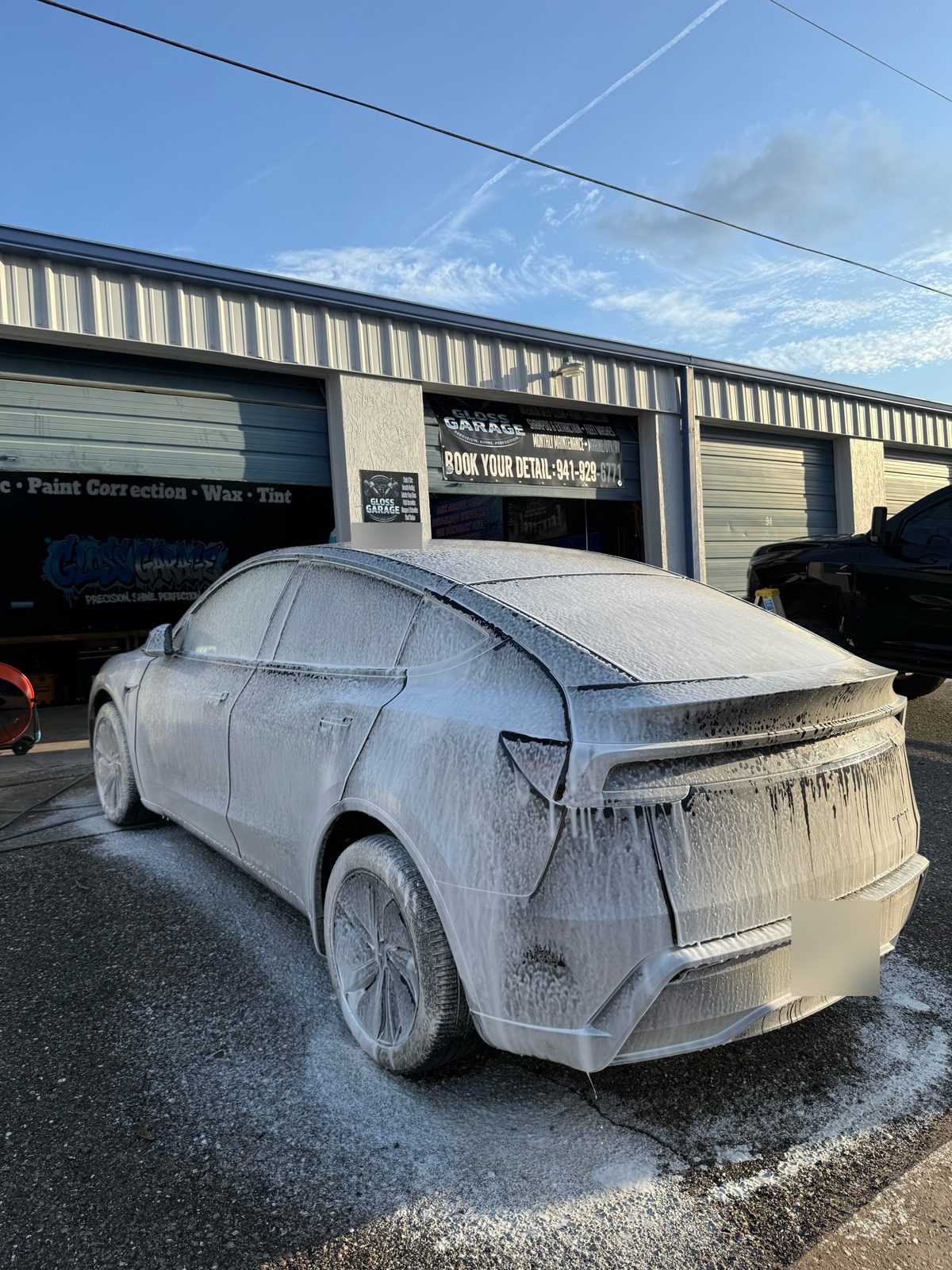 Tesla covered in foam during a hand wash outside the Gloss Garage shop