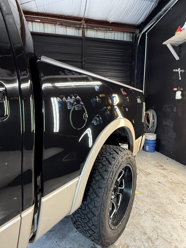 The same bed side and fuel door after correction, deep black gloss