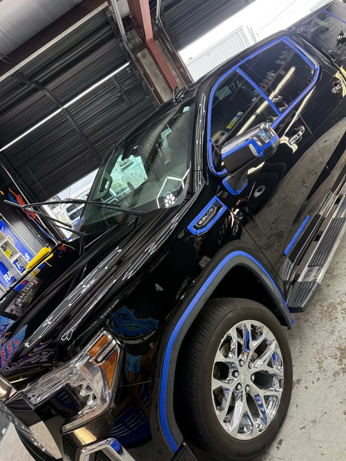 Black GMC Sierra with trim masked in blue tape for paint correction